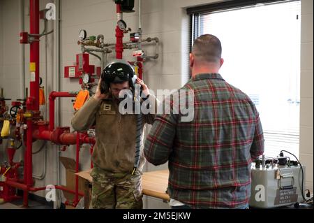 USA Air Force Master Sgt. Kris Harmon, ein Flugzeugtechniker, der dem 180. Kampfflugflügel der Ohio National Guard zugeteilt ist, demonstriert mit dem Combined Air Crew System Tester. Oder BEI einem Besuch mit Kadetten des Reserve Officer Training Corps der Bowling Green State University auf der 180FW in Swanton, Ohio, am 8. März 2022, eine Maschine zur Überprüfung auf Sauerstofflecks während eines Helmmontierens. Die 180FW bot die Gelegenheit, eine einsatzbereite Einheit der Luftwaffe zu sehen und mehr über die Einsatzmöglichkeiten und Fähigkeiten des Flügels zu erfahren, während die Kadetten beginnen, Karrierewege nach dem zu erwägen Stockfoto