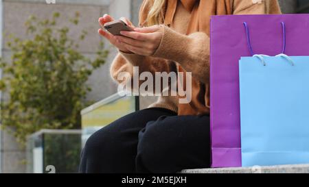 Freigestellte Ansicht nahe weibliche Hände beim Kauf von Telefonen im Internet-Shop-Lieferservice. Eine nicht wiedererkennbare Frau, die online einkauft, während ein Telefonmädchen sitzt Stockfoto