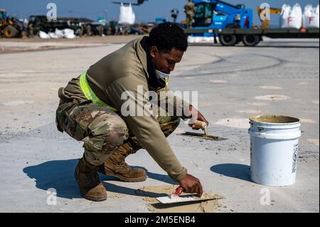 Ein 8. Civil Engineer Squadron augmentee Airman füllt während des Rapid Airfield Damage Repair Trainings am Luftwaffenstützpunkt Kunsan, Republik Korea, am 9. März 2022 Spälle, im Wesentlichen dort, wo Beton abgeplatzt ist. Das Training von Flugzeugen aus verschiedenen Einheiten im Wolf Pack gewährleistet die kontinuierliche RADR-Fähigkeit und somit den Flugbetrieb. Stockfoto