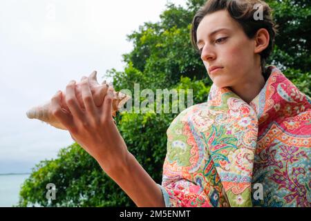 Ein weißer Teenager mit einer riesigen Muschel Stockfoto