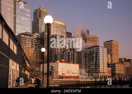 WA22873-00...WASHINGTON - Fußweg entlang der Seite des Seattle Aquarium an der Elliott Bay mit den Seattle Highhrises hinter dem Sonnenuntergang. Stockfoto