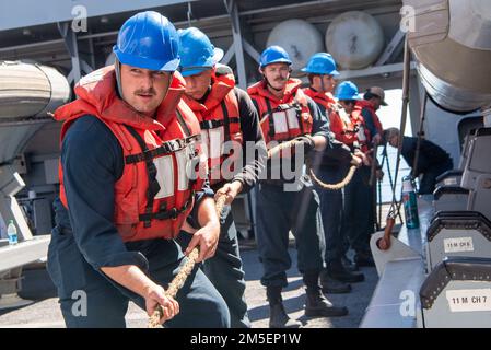 Matrosen an Bord des Amphibien-Transportlagers USS Anchorage (LPD 23) heave line während einer Wiederauffüllung auf See mit Flottenauffüllungsöler USNS Pecos (T-AO 197), März 8. Anchorage führt Routineeinsätze in der US-3.-Flotte durch. Stockfoto