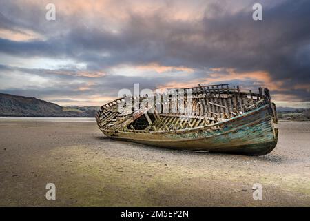 Verlassenes Fischerboot an einem walisischen Strand bei Sonnenuntergang Stockfoto