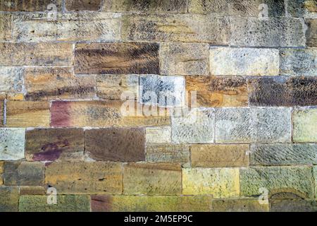 Alte Ufermauer mit wunderschönen farbigen Steinen Stockfoto
