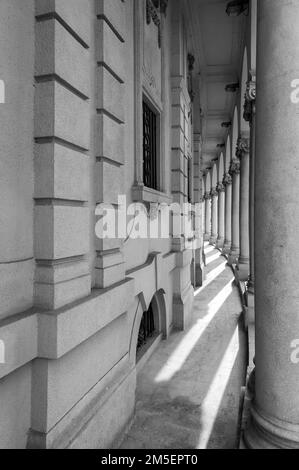 Eine Schwarz-Weiß-Wand mit gebogenen Arkadenwänden und eine Reihe von Steinpfählen Stockfoto