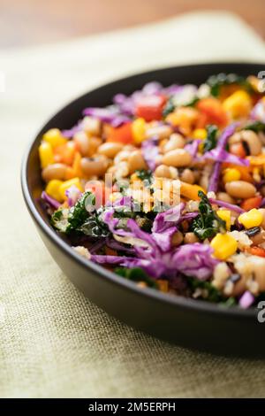 Farbenfroher schwarzäugiger Erbsen- und Grünkohlsalat mit Quinoa, Mais, Paprika, Karotten und Purpurkohl. Stockfoto