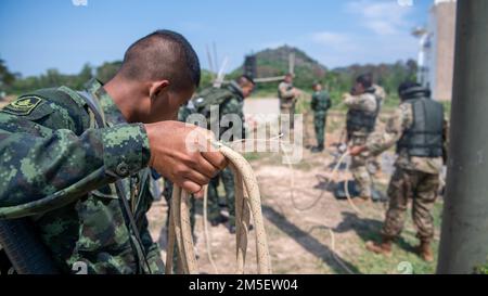 Ein gemeinsames Trupp von Soldaten der Alpha Company, des 29. Brigadeingenieurbataillons, des 3. Brigadekampfteams, der 25. Infanteriedivision und der Royal Thai Army bereitet ein Seil für eine Wasserüberquerung während einer Einseilbrückenübung vor, 9. März 2022, Fort Thanarat, Thailand. Soldaten der Royal Thai Army teilten ihr Wissen und leiteten die Ausbildung zum Überqueren von Gewässern mit Soldaten während Hanuman Guardian 22, um die Bereitschaft zu erhöhen und die Interoperabilität zwischen den beiden Truppen zu entwickeln. Stockfoto