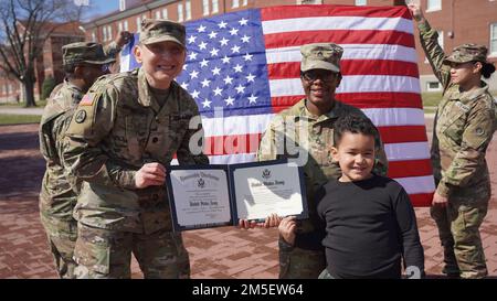 LT. Oberstleutnant Nadiya Bryant, Leiter der Materialverwaltung, Support Operations, 1. Theater Sustainment Command, gratuliert Staff Sgt. Kierra Magee, Abteilung Materialverwaltung, nicht kommissionierter Offizier, SPO, 1. TSC, mit ihrem Sohn, nach ihrer Wiedereinstellung während einer Zeremonie in Fort Knox, Kentucky, 9. März 2022. Magee wird die TSC 1. verlassen und ihre nächste Aufgabe in Louisville als Anwerber fortsetzen. Stockfoto