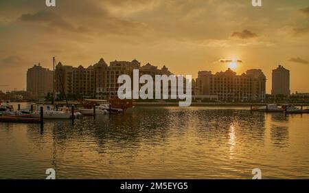 Porto Arabia Marina in der Perle Doha, Katar Sunset Shot mit Yachten und Booten vor Anker im Yachthafen mit Wohngebäuden im Hintergrund. Stockfoto