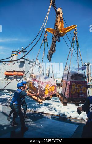 220303-N-TT059-1323 SÜDCHINESISCHES MEER (10. MÄRZ 2022) USA Navy-Matrosen leiten Fracht während einer Wiederauffüllung auf See (RAS) mit dem Flottenöler USNS John Ericson (T-AO 194) an Bord der Guided-Missile Destroyer USS Momsen (DDG 92). Momsen ist dem Befehlshaber der Task Force 71/Destroyer Squadron (DESRON) 15, dem größten vorwärtsstationierten DESRON der Marine und der Hauptstreitkräfte der US-7.-Flotte zugewiesen und unterstützt derzeit ein freies und offenes Indo-Pacific. Stockfoto