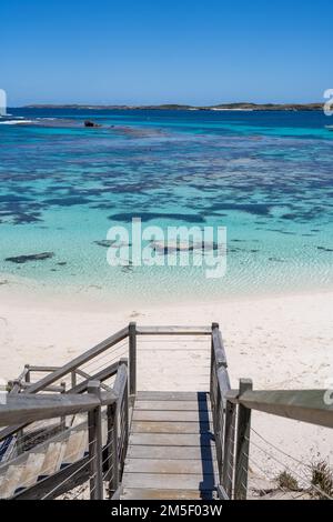 Ein vertikales Hochwinkelfoto einer hölzernen Treppe an der Küste eines Ozeans an einem sonnigen Tag Stockfoto