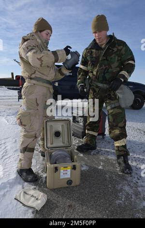 USA Air Force Notfallmanagement-Mitglieder von links nach rechts Senior Airman Elyssa Johnson, Und Staff Sgt. Caleb McNeil, beide Mitglieder der 114. Civil Engineer Squadron, Sioux Fall, South Dakota Air National Guard, richteten chemische, biologische, radiologische und nukleare (CBRN) Detektionsgeräte während einer Übung auf der North Dakota Air National Guard Regional Training Site, Fargo, North Dakota, 9. März 2022 ein. Sie nehmen an einem CBRN-Schulungskurs für kaltes Wetter Teil, um mehr über die Herausforderungen zu erfahren, die sich bei der Durchführung von Notfallmaßnahmen bei extrem kalten Temperaturen stellen. Stockfoto