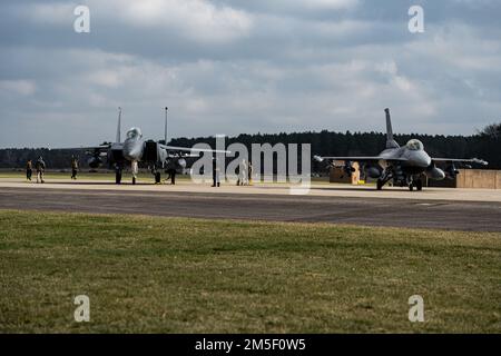 EIN US-AMERIKANISCHER Air Force F-15E Strike Eagle, Left, der 494. Kampfgeschwader zugeteilt, und ein F-16C Fighting Falcon der 510. Kampfgeschwader, werden vor dem Start in Royal Air Force Lakenheath, England, am 9. März 2022 auf einer Waffenstelle in Schlange gestellt. Der 48. Fighter Wing, die Gasteinheit der RAF Lakenheath, arbeitet regelmäßig mit Partnereinheiten in ganz Europa zusammen, um die Interoperabilität zu vertiefen und die transatlantische Allianz zu stärken. Stockfoto