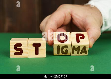 Medizinisches Konzept. Auf einer grünen Oberfläche legt ein Mann Würfel mit der Inschrift - STOPP, STIGMA Stockfoto