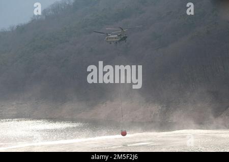 Soldaten der Combat Aviation Brigade 2., 2. Infantry Division/ROK-US Combined Division unterstützen südkoreanische Feuerwehrleute bei der Bekämpfung von Waldbränden in der Nähe von Uljin, Republik Korea, 10. März 2022. Die Brigade setzt CH-47 Chinook und UH-60 Blackhawk-Hubschrauber ein, die mit einem Bambi-Eimer konfiguriert sind, um Wasser auf die Brände zu Tropfen, um der Republik Korea zu helfen, die Ausbreitung des Feuers zu stoppen. Stockfoto