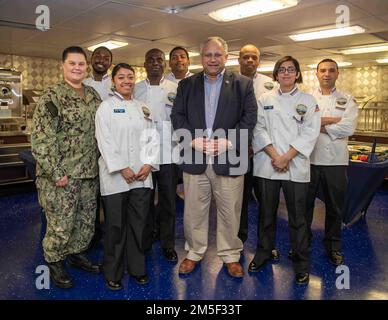 Der Sekretär der Marine Carlos Del Toro und Matrosen, die der Versorgungsabteilung der USS Gerald R. Ford (CVN 78) zugeteilt wurden, posieren für ein Gruppenfoto in der vorderen Garderobe während eines Schiffsbesuchs am 10. März 2022 zur Unterstützung der hundertjährigen Flotte von Flugzeugträgern. An Bord führte Del Toro ein Telefonat mit der Besatzung durch, um sie zu ihrem Erfolg während der geplanten inkrementellen Verfügbarkeit des Schiffes zu beglückwünschen, und traf mit der Leitung von Ford zusammen, um die einzigartigen Fähigkeiten der Ford-Klasse vor dem Einsatz des Schiffes im Jahr 2022 zu erörtern. Stockfoto