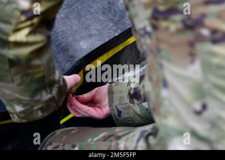 Ein in-Place Patient Decon (IPPD)-Teammitglied der 8. Medical Group drängt sich während einer Routineschulung am Kunsan Air Base, Republik Korea, am 10. März 2022, zur Montage von Dekontaminationsschutzsystemen. Das IPPD-Team baute ein Dekontaminationsschutzsystem zusammen, in dem simulierte Patienten sicher dekontaminiert wurden, bevor sie zur Behandlung in eine nahe gelegene medizinische Einrichtung gebracht wurden. Stockfoto