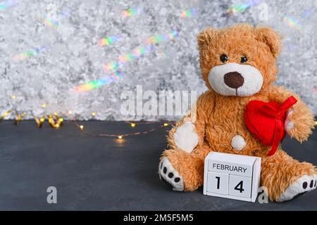 Brauner Teddybär. Rotes Herz und Holzkalender Valentinstag - 14. Februar. Hochwertiges Foto Stockfoto