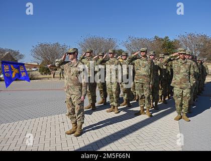 Mitglieder des 316. Trainingsgeschwaders salutieren während einer vierteljährlichen Zeremonie vor dem Norma Brown-Gebäude, Goodfellow Air Force Base, Texas, 10. März 2022, während die amerikanische Flagge absinkt. Während des Rückzugs kommen uniformierte Mitglieder zur Aufmerksamkeit und salutieren bei den ersten Noten von „To the Colors“ oder der Nationalhymne, die beim Absenken der Flagge gespielt wird. Stockfoto