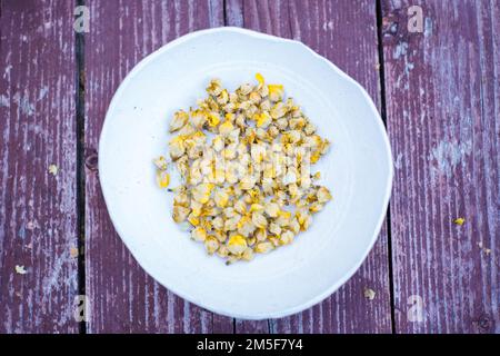 Trockener Kräutertee aus großen Mulleinblüten oder Verbascum thapsus in einer kleinen Tonschüssel mit Holzhintergrund. Stockfoto