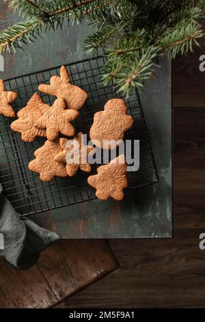 Weihnachtskekse oder Lebkuchen in verschiedenen Formen auf einem Teigregal auf einem grünen Holztisch. Weihnachtskomposition oder Neujahrskomposition mit weihnachtsbaum, bis Stockfoto