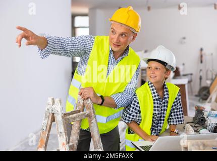 Der junge Junge und sein Vater besprechen den Arbeitsplan in einer neuen Wohnung Stockfoto