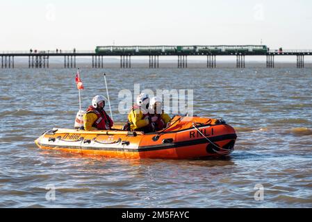 Mitglieder der Southend RNLI üben in der Nähe von Southend Beach. Sie fahren am Ende des dahinter liegenden Piers, wobei der Zug vorbeifährt. Klasse D D818 Stockfoto