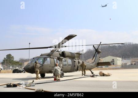 Soldaten, die dem 2-2. Angriffshubschrauber-Bataillon zugeteilt wurden, tanken einen UH-60 Blackhawk-Hubschrauber auf, um die Feuerwehr in der Nähe der Stadt Daegu fortzusetzen. Stockfoto