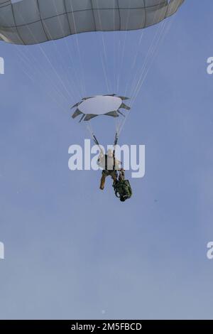 Ein Fallschirmjäger aus dem 1. Bataillon, 501. Fallschirm-Infanterie-Regiment, 4. Brigade, 25. Infanteriedivision der US-Armee Alaska, senkt seinen Rucksack, während er in den Donnelly-Trainingsbereich springt, als Teil einer Joint Forcible Entry Operation nahe Fort Greely, AK, März 11, 2022 ist Teil des Joint Pacific Multinational Readiness Center 22-02. JPMRC 22-02, ausgeführt in Alaska mit seinen erstklassigen Trainingseinrichtungen und der rauen arktischen Umgebung, baut Soldaten und Anführer zu einem Team aus erfahrenen, harten, aufmerksamen und anpassungsfähigen Kriegern zusammen, die in der Lage sind, einen zu bekämpfen und zu gewinnen Stockfoto