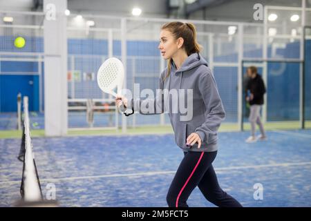 Frau, die beim Padel auf dem Platz den Ball servierte Stockfoto