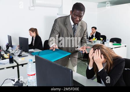 Unzufriedene Managerin, die an einem Laptop arbeitet, und wütender männlicher Boss, der auf Fehlschläge bei der Arbeit hinweist Stockfoto
