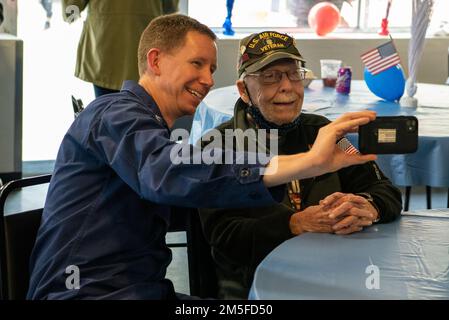 Captain Jason Smith, Commander, Coast Guard Sector Houston-Galveston, macht ein Foto mit einem Veteranen während einer kombinierten Freiwilligenveranstaltung der Federal Campaign bei einem Houston Veteran's Home in Houston, Texas, am 11. März 2022. Mitglieder kochten und trennten das Mittagessen für Einheimische neben den USA ab Immigration and Customs Enforcement und das Michael E. DeBakey Veterans Affairs Medical Center als Teil einer Freiwilligenveranstaltung in Zusammenarbeit mit den USA Veteranen Houston und die Veteran Initiative. Stockfoto