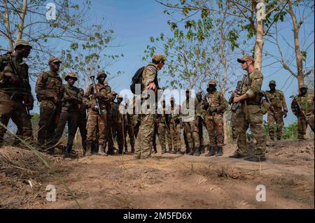 USA Green Berets der Armee, die der 3. Special Forces Group (Airborne) zugeteilt sind, zeigen beninesischen Soldaten des 1. Kommando-Fallschirmbataillons, wie sie Anzeichen dafür identifizieren, dass sich in Ouassa (Afrika) am 11. März 2022 ein improvisierter Sprengkörper befindet. Das Engagement der USA bringt beiderseitigen Nutzen, hält internationale Normen ein und behandelt Partner als gleichberechtigt. Stockfoto