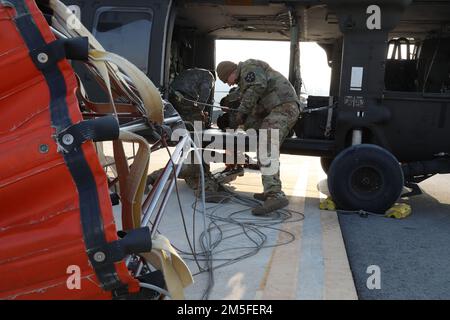 Soldaten des 2-2. Angriffshelikopter-Bataillons, 2. Kampfluftfahrtbrigade, 2. Infanteriedivision-ROK/US Combined Division, bereiten die Befestigung des Bambi-Eimer-Gurtes an UH-60 Blackhawk, USAG Daegu-Carroll, 11. März 2022 vor. Die Besatzungsmitglieder stellen vor jedem Flug sicher, dass der Anschlagbolzen ordnungsgemäß befestigt ist. Stockfoto