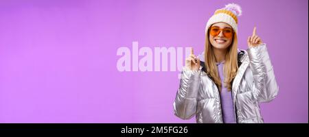 Freudig energetisiert unterhalten nette blonde Frau mit Spaß genießen Sie Urlaub Verschneite Bergtour trägt Sonnenbrille Silber Jacke Winter Hut tanzen Stockfoto