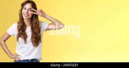 Positive aufgeschlossen enthusiastisch gut aussehende Frau mit Spaß genießen Wochenende Sommerurlaub Reise zeigen Friedenszeichen Sieg Geste auf Auge kippen Kopf Stockfoto