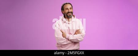 Prooud erfolgreiche verträumt glücklich Erwachsenen bärtigen Mann Urlaub genießen sorglos Leben lachen glücklich Kreuz Arme Brust zuversichtlich Blick zur Seite erreicht Stockfoto