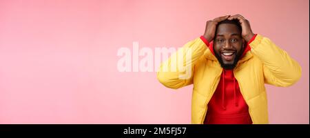 Taille-up überrascht glücklich glücklich junge afroamerikanische bärtige Männchen in gelb Jacke hält Hände Kopf lächelnd beeindruckt freudig erhalten genial Stockfoto