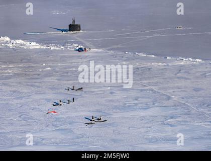 Mitglieder der Naval Special Warfare führen einen Sprung in großer Höhe mit niedriger Öffnung über das schnell angreifende U-Boot USS Pasadena (SSN 752) der Los Angeles-Klasse auf der ICEX durch, der zeitgleich mit der 2022 Arctic Edge Übung stattfand. Arctic Edge ist ein US-amerikanischer Markt Zweijährliche Verteidigungsübung des nördlichen Kommandos, die die Fähigkeit demonstrieren soll, sich schnell in der Arktis zu stationieren und zu operieren. Stockfoto