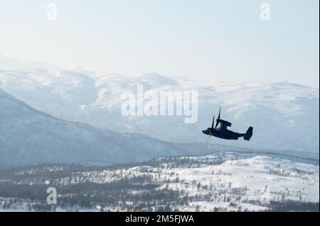 Ein US Air Force CV-22B Osprey, der dem 352d Special Operations Wing zugewiesen wurde, fliegt um die Berge Nordnorwegens, während er von einem UH-1Y Venom und einer AH-1W Super Cobra, die dem 2. Marine Aircraft Wing zugewiesen wurde, während einer simulierten Landezone für feindliche Kämpfe, 12. März 2022, Während des Trainings Kaltantwort ‘22. Diese Schulung wurde durchgeführt, um jede Einheit besser mit den Taktiken und Protokollen der jeweils anderen Einheit vertraut zu machen. Übung Cold Response '22 ist eine jährliche norwegische nationale Bereitschafts- und Verteidigungsübung, die in ganz Norwegen stattfindet, an der jeder seiner Militärdienste, Stockfoto