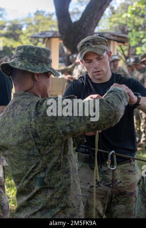 Ein Schulungsleiter für Dschungeloperationen unterstützt einen Soldat der philippinischen Armee im Lehrplan für Knotenbindung als Teil des JOTC mit den USA Armee-Pazifiksoldaten mit 2. Bataillons, 27. Infanterie-Regiment, 3. Infanterie-Brigaden-Kampfteam, 25. Infanterie-Division, während Salaknib 2022, in Fort Magsaysay, Nueva Ecija, Philippinen, 12. März 2022. Salaknib wird jährlich von der philippinischen Armee geführt Von der Army Pacific gesponserte bilaterale Übung zur Verbesserung der Kapazitäten und der Interoperabilität der US-amerikanischen und der philippinischen Armee im gesamten Spektrum militärischer Operationen und zur Stärkung der Verbindungen zwischen den Truppen Stockfoto