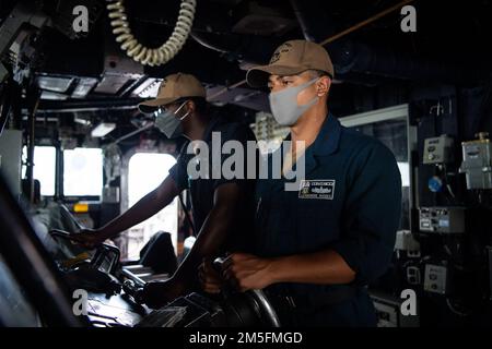 PHILIPPINE SEA (14. März 2022) Boatswain’s Mate Seaman Leamondre Rhodes, von St. Louis und Seaman Jayson Belser aus Mobile, Alabama, übernehmen das Ruder an Bord der Arleigh-Burke-Klasse-Guided-Missile Destroyer USS Dewey (DDG 105), während sie laufende Routineeinsätze im Zuständigkeitsbereich der US-7.-Flotte durchführen. Dewey ist der Destroyer-Staffel (DESRON) 15 zugeteilt und unterstützt derzeit ein freies und offenes Indo-Pacific. CTF 71/DESRON 15 ist die größte nach vorn verlegte DESRON-Flotte der Marine und die größte Oberflächenkraft der US-7.-Flotte. Stockfoto