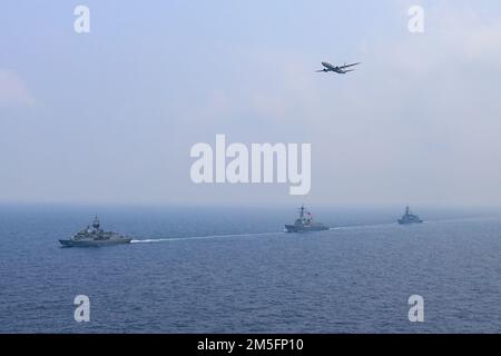 220315-N-TT059-1007 SÜDCHINESISCHES MEER (15. März 2022) der geführte Raketenzerstörer USS Momsen (DDG 92), die Fregatte der RANG Anzac-Klasse HMAS Arunta (FFH 151) und der JMSDF-gesteuerte Raketenzerstörer JS Yuudachi (DD 103) durchqueren das Südchinesische Meer, während ein P-8A Poseidon während eines trilateralen Trainings vorbeifliegt. Momsen ist dem Befehlshaber der Task Force 71/Destroyer Squadron (DESRON) 15, dem größten vorwärtsstationierten DESRON der Marine und der Hauptstreitkräfte der US-7.-Flotte zugewiesen und unterstützt derzeit ein freies und offenes Indo-Pacific. Stockfoto