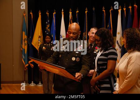 Generalmajor Michel M. Russell Sr., kommandierender General, 1. Theater Sustainment Command, überreicht ein Geschenk an Razell Perry, Ehefrau von Kommandoleiter Major Michael J. Perry III, während einer Zeremonie zur Aufgabe der Verantwortung in Fort Knox, Kentucky, am 15. März 2022. Russell dankte Frau Perry und ihrer Familie für ihre kontinuierliche Unterstützung und ihre Opfer. Stockfoto