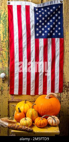 Die Amerikanische Flagge Hängt An Der Altgelben Holztür Mit Kürbissen Im Herbst Auf Dem Altgelben Tisch Still Life Stockfoto