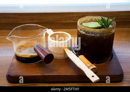 Espresso mit schwarzem Kaffee, braunem Zuckerrohr und eiskaltem Zitronentee auf einem Holztablett im japanischen Stil für thai-Reisende essen Getränke in klassischem Stil Stockfoto