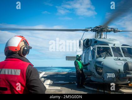 220315-N-FS190-1120 ATLANTISCHER OZEAN (15. März 2022) Aviation Ordnanceman 2. Class Stephen Byrd beobachtet einen MH-60R Sea Hawk Helikopter, der an die „Großmeister“ des Helicopter Maritime Strike Squadron (HSM) 46 angehängt ist, auf dem Flugdeck des Arleigh Burke-Class Guided-Missile Destroyer USS Truxtun (DDG 103, TFEX), Task Force Übung 15. März (TFEX) 2022. TFEX ist eine szenariobasierte Übung, die als Zertifizierung für unabhängige Schiffe dient und dazu bestimmt ist, die Einsatzbereitschaft und -Leistung im integrierten Betrieb zu testen. Truxtun ist im Begriff, eine Schulung für die Carrier Strike Group (CSG) 4 durchzuführen Stockfoto