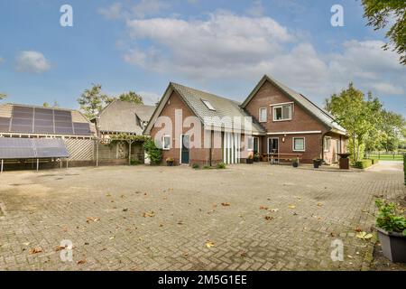 Ein Haus mit Sonnenkollektoren auf dem Dach und einigen Bäumen im Hinterhof, von der anderen Straßenseite aus gesehen Stockfoto