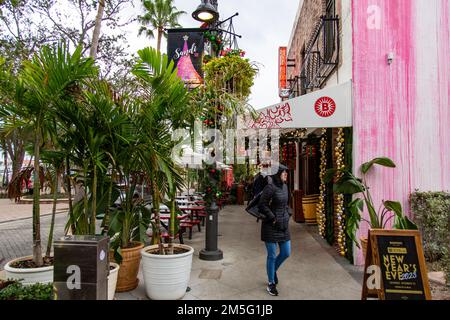 Eine Frau im Mantel geht an einem ungewöhnlich kalten Wintertag in West Palm Beach, Florida, USA, am Restaurant Bodega Taqueria y Tequila vorbei. Stockfoto