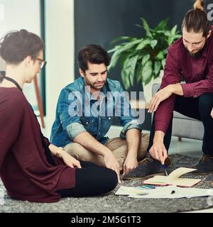 Durchsuchen der neuesten Projektaktualisierungen. Eine Gruppe junger Kreativer, die ein Meeting in einem modernen Büro abhalten. Stockfoto